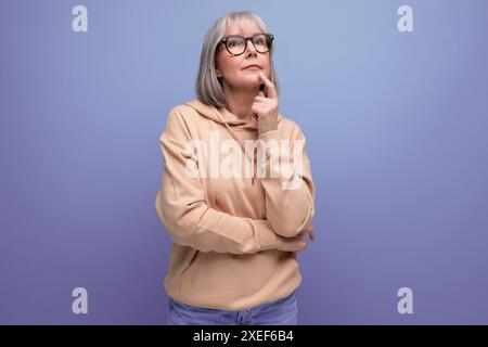 Portrait d'une gentille grand-mère de femme d'âge moyen avec les cheveux gris dans un look de jeunesse décontracté sur un fond de studio avec espace de copie Banque D'Images
