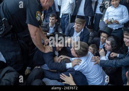 Beni Brak, Israël. 27 juin 2024. Les Juifs ultra orthodoxes se bagarrent avec la police anti-émeute israélienne alors qu'ils bloquent l'autoroute dans un sit-in de protestation contre le service militaire obligatoire en Israël. Les neuf juges de la Cour suprême de Jérusalem ont jugé qu'il n'y avait pas de fondement juridique pour exempter les ultra-orthodoxes du service militaire obligatoire et ont approuvé deux requêtes demandant leur conscription immédiate. Crédit : Ilia Yefimovich/dpa/Alamy Live News Banque D'Images