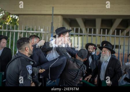 Beni Brak, Israël. 27 juin 2024. Les Juifs ultra orthodoxes se bagarrent avec la police anti-émeute israélienne alors qu'ils bloquent l'autoroute dans un sit-in de protestation contre le service militaire obligatoire en Israël. Les neuf juges de la Cour suprême de Jérusalem ont jugé qu'il n'y avait pas de fondement juridique pour exempter les ultra-orthodoxes du service militaire obligatoire et ont approuvé deux requêtes demandant leur conscription immédiate. Crédit : Ilia Yefimovich/dpa/Alamy Live News Banque D'Images