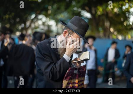 Beni Brak, Israël. 27 juin 2024. Un juif ultra orthodoxe lit de la Torah lors d'une manifestation contre le service militaire obligatoire en Israël. Les neuf juges de la Cour suprême de Jérusalem ont jugé qu'il n'y avait pas de fondement juridique pour exempter les ultra-orthodoxes du service militaire obligatoire et ont approuvé deux requêtes demandant leur conscription immédiate. Crédit : Ilia Yefimovich/dpa/Alamy Live News Banque D'Images