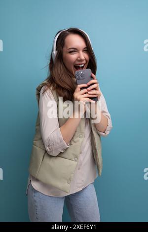 Jeune femme brune énergique se relaxant à la musique en utilisant des écouteurs et un téléphone portable Banque D'Images