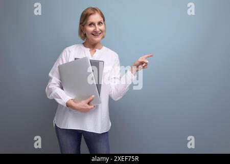 Femme mature avec les cheveux blonds travaille à distance en utilisant un ordinateur portable Banque D'Images