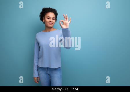 Portrait latina brune femme avec les cheveux ondulés dans des vêtements décontractés élégants bleus Banque D'Images