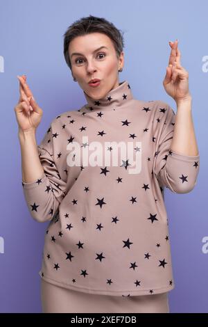 Jeune femme carriériste bien entretenue avec les cheveux striés gris habillé dans une jupe et un chemisier espérant bonne chance Banque D'Images