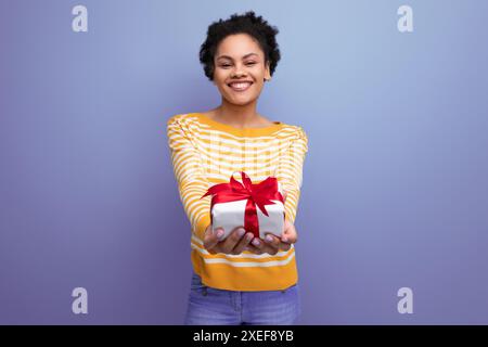 Happy afro brunette 20s latin jeune femme tenant une boîte cadeau Banque D'Images