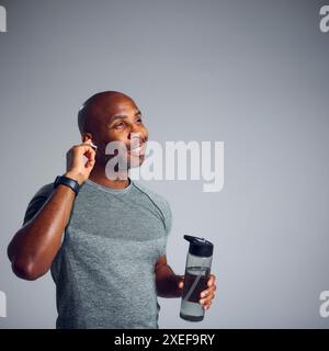 Prise de vue en studio d'un homme d'âge mûr dans des vêtements de fitness en streaming vers des écouteurs sans fil de Smart Watch Banque D'Images