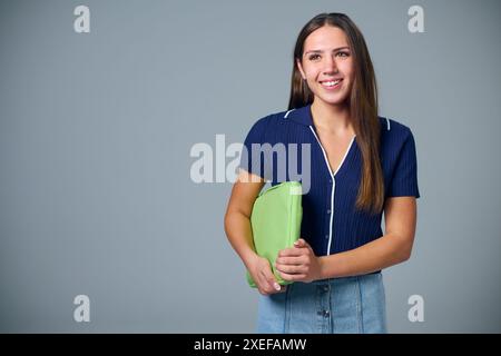 Studio Portrait de Smiling Female College ou University Student avec sac pour ordinateur portable sur fond gris Banque D'Images