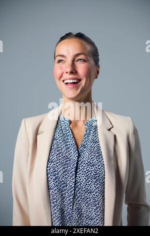 Studio Portrait de femme d'affaires souriante portant costume sur fond gris Banque D'Images