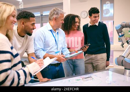 Groupe d'étudiants en ingénierie collégiale ou universitaire en classe de robotique avec professeur masculin Banque D'Images