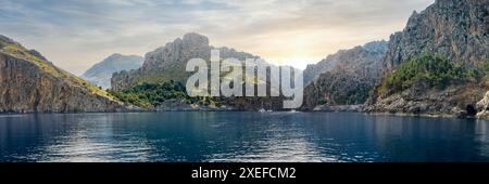 La baie de Cala de sa Calobra, avec la lumière du soleil du matin projetant une lueur sereine sur le paysage idyllique, une image idéale pour promouvoir des excursions en bateau. Banque D'Images