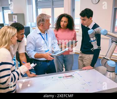 Groupe d'étudiants en ingénierie collégiale ou universitaire en classe de robotique avec professeur masculin Banque D'Images