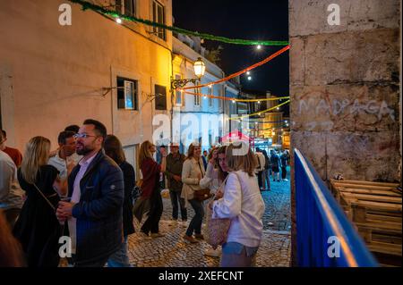 Les gens se rassemblent sous des guirlandes colorées à Madragoa, Lisbonne, célébrant le festival Santo António par une chaude nuit d'été. Banque D'Images
