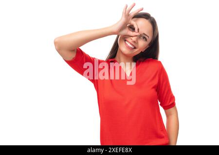 Portrait en gros plan d'une drôle jeune brune européenne dame dans un t-shirt rouge avec une grimace Banque D'Images