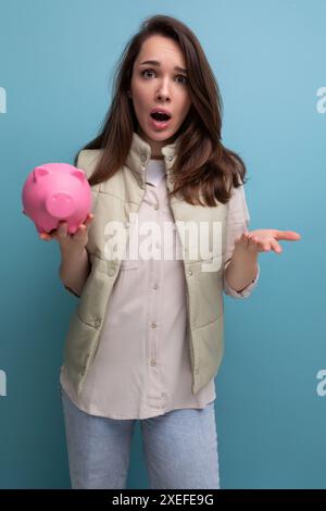Jeune femme brune avec une tirelire rose dans les mains Banque D'Images