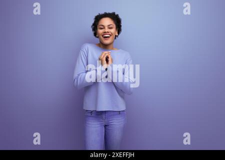 Jolie jeune femme latine avec des cheveux afro dans des vêtements de printemps élégants flirtant Banque D'Images