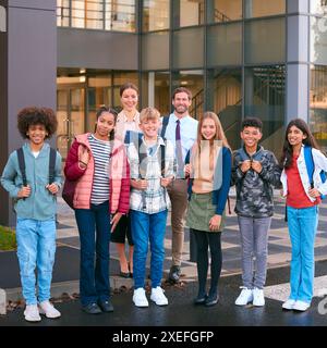 Portrait de la classe des élèves du secondaire ou du secondaire debout à l'extérieur du bâtiment de l'école avec des enseignants Banque D'Images