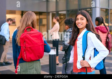 Portrait d'une étudiante du secondaire ou du secondaire à l'extérieur du bâtiment de l'école avec des enseignants et des élèves Banque D'Images