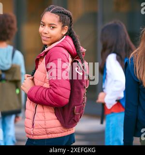 Portrait d'une étudiante du secondaire ou du secondaire à l'extérieur du bâtiment de l'école avec des enseignants et des élèves Banque D'Images