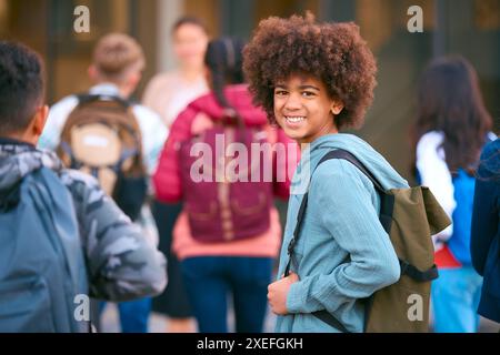 Portrait d'un étudiant masculin du secondaire ou du secondaire à l'extérieur du bâtiment scolaire avec des enseignants et des élèves Banque D'Images