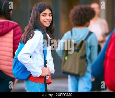 Portrait d'une étudiante du secondaire ou du secondaire à l'extérieur du bâtiment de l'école avec des enseignants et des élèves Banque D'Images