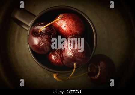 Cerises fraîches dans une tasse noire gros plan Banque D'Images