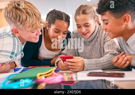 Élèves du secondaire ou du secondaire dans la zone d'étude travaillant ensemble à l'aide de téléphones portables Banque D'Images