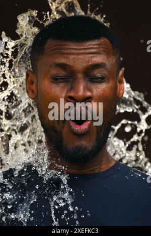 Visage d'un jeune homme noir trempé avec de l'eau froide par une chaude journée d'été en format vertical Banque D'Images