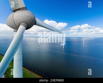 Une éolienne se tient haute dans le vaste océan, ses pales tournent gracieusement dans la brise du printemps, exploitant la puissance du W. Banque D'Images