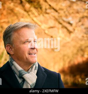 Homme senior souriant sur la promenade à travers le parc d'automne ou la campagne Banque D'Images