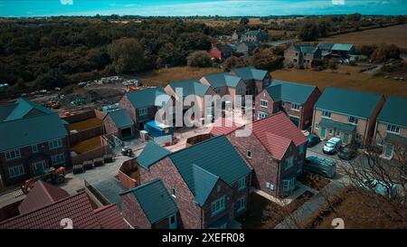 Vue aérienne d'un quartier de banlieue avec des maisons nouvellement construites, entouré de verdure et de champs. Les équipements et matériaux de construction sont visi Banque D'Images