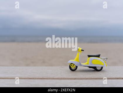 Nature morte. Un petit cyclomoteur se tient sur un arbre léger sur fond de mer et de sable blanc. Vacances d'été . Carte postale. Copier l'espace. Banque D'Images