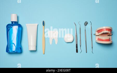 Bain de bouche, tube de dentifrice, fil dentaire et miroir médical sur fond bleu, hygiène buccale. Banque D'Images