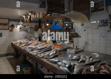 Poissonnier en attente pour les clients au marché à Isola di Ortigia dans le centre-ville de Syracuse Banque D'Images