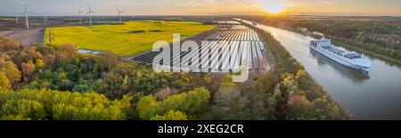 Panneaux solaires photovoltaïques montés au sol, parc éolien voisin du canal, où le navire gracieusement Banque D'Images