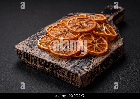 Tranches rondes séchées de mandarine, d'orange ou de citron sur fond de béton foncé Banque D'Images