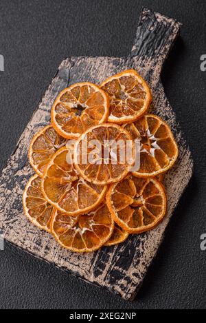 Tranches rondes séchées de mandarine, d'orange ou de citron sur fond de béton foncé Banque D'Images