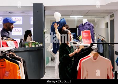 Chaos du vendredi noir. Les clients de gens de shopping diversifiés se précipitent pour acheter des vêtements à rabais tout en magasinant dans le magasin de vêtements pendant les ventes saisonnières, les acheteurs devenant fous à la recherche de bonnes affaires Banque D'Images