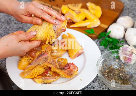 Les mains des femmes frottent des épices sur des morceaux de viande de poulet Banque D'Images