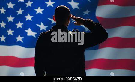 Soldat américain faisant un geste de salutation de la main vers le drapeau américain dans le centre de commandement, montrant du respect. Unité militaire en uniforme servant dans les forces armées des États-Unis, faisant des gestes patriotiques, caméra A. Banque D'Images