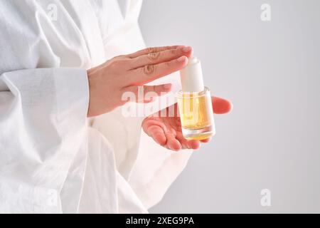 Sérum bleu avec pipette dans une femme mains dans une robe. Banque D'Images