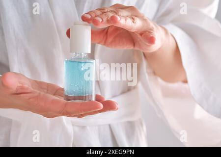 Sérum bleu avec pipette dans une femme mains dans une robe. Banque D'Images