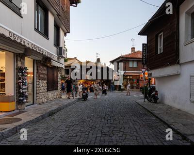 Touristes se promenant dans une rue pavée étroite bordée de boutiques et de restaurants au crépuscule à ohrid, en macédoine du Nord Banque D'Images