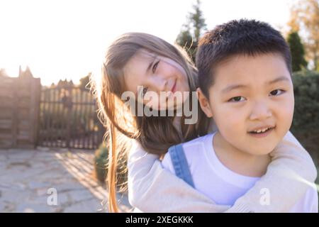 Deux petits enfants de races différentes jouent dans le jardin en plein air. Un garçon asiatique et une fille caucasienne s'amusent Banque D'Images