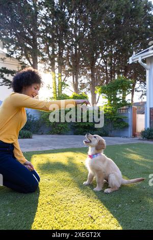 Jouer avec chiot, chien de formation de femme avec jouet dans la cour arrière Banque D'Images