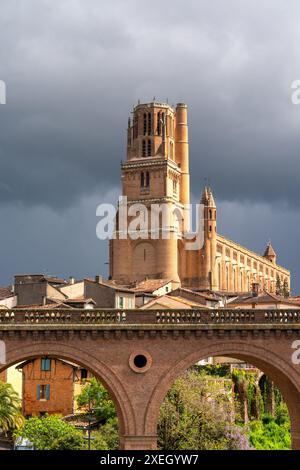 Vue de la cathédrale historique de Saninte-Cécile en briques rouges et du pont ferroviaire à Albi sous un ciel sombre et inquiétant Banque D'Images