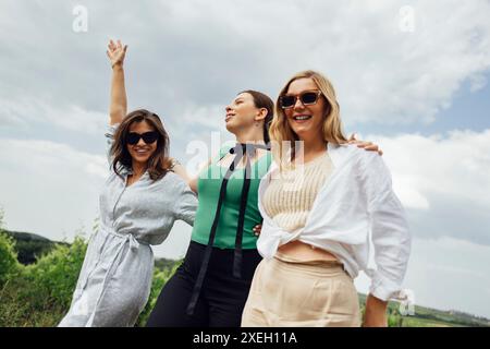 Trois jeunes femmes s'embrassent et marchent sur le vignoble. Banque D'Images