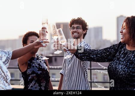 Une fille à la peau foncée verse du champagne dans les verres de ses amis multinationaux Banque D'Images