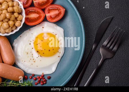 Œufs de poule frits, saucisses, tomates cerises, pois chiches, épices, sel et herbes Banque D'Images