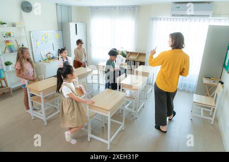 Enseignant et élèves, le matin pour commencer à apprendre et étudier dans une salle de classe de l'école. Banque D'Images