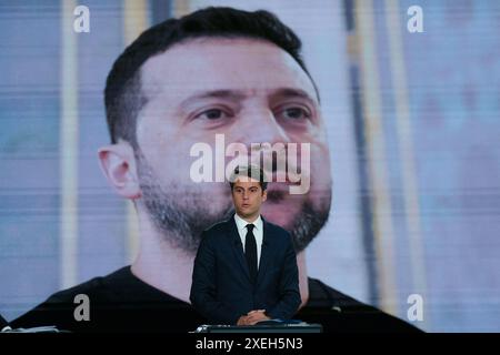 Paris, France. 27 juin 2024. Le premier ministre français Gabriel Attal se tient devant un écran montrant une photo du président ukrainien Volodymyr Zelensky lors d'un débat politique avec le premier secrétaire du Parti socialiste de gauche (PS) et député français Olivier Faure et le président et chef du parti d'extrême droite rassemblement National (RN) L'eurodéputé Jordan Bardella a diffusé sur la chaîne de télévision française France 2 à Paris le 27 juin 2024, à l'approche des élections anticipées en France pour une nouvelle Assemblée nationale. Photo Dimitar Dilkoff/Pool/ABACAPRESS. COM Credit : Abaca Press/Alamy Live News Banque D'Images